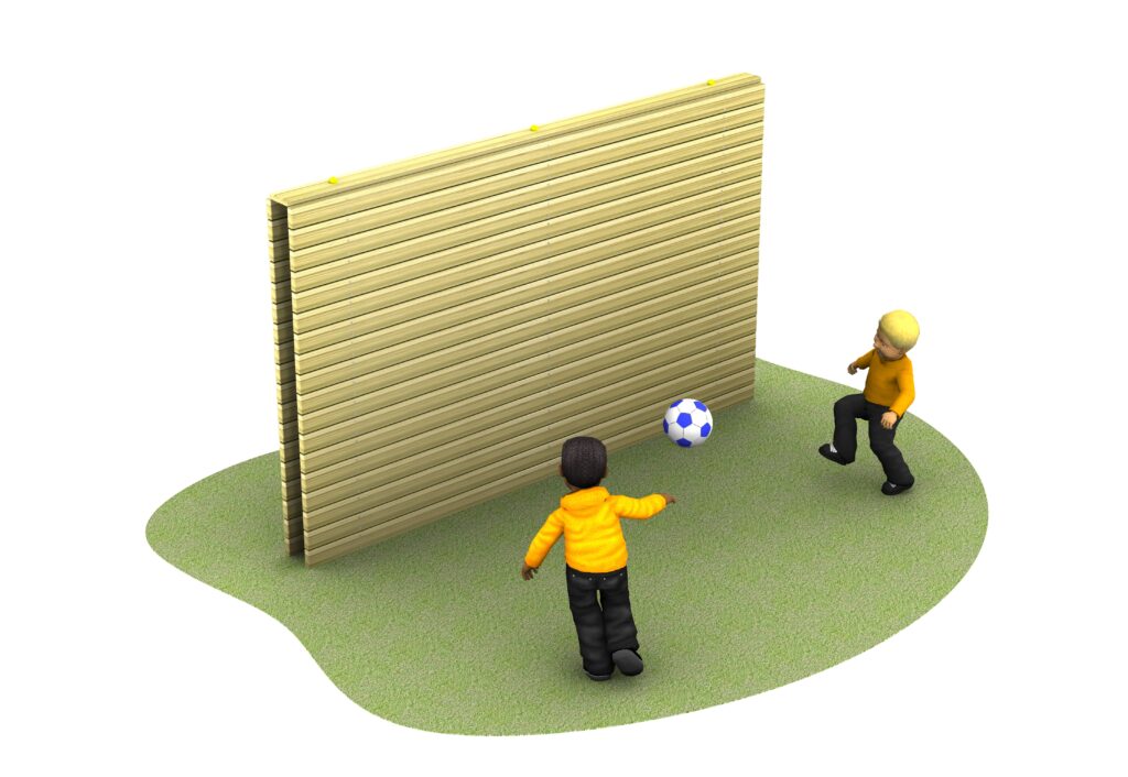 Two children in orange jackets play football, kicking a blue and white ball towards a tall wooden wall on a patch of grass.