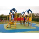 Children playing on a colourful outdoor playground structure featuring the Belair Tower 900mm with Poly Slide, climbing nets, and ladders on a soft blue and green play surface.