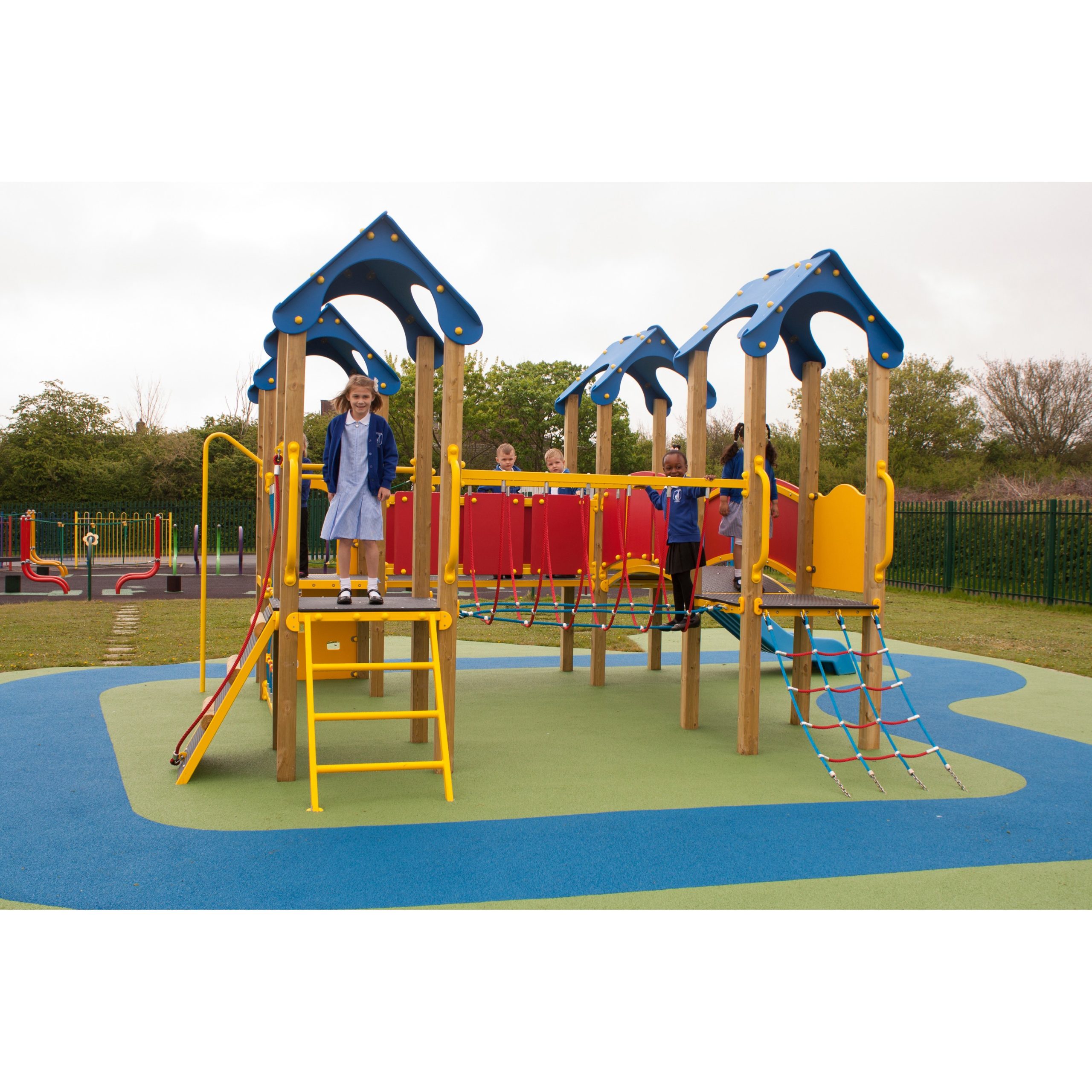 Children playing on a colourful outdoor playground structure featuring the Belair Tower 900mm with Poly Slide, climbing nets, and ladders on a soft blue and green play surface.
