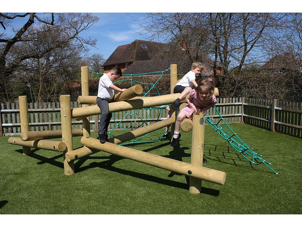 Three children in school uniforms climb and play on a wooden and rope climbing frame in an outdoor playground with artificial grass.