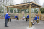 4 legged shade pergola with children sitting on the benches underneath