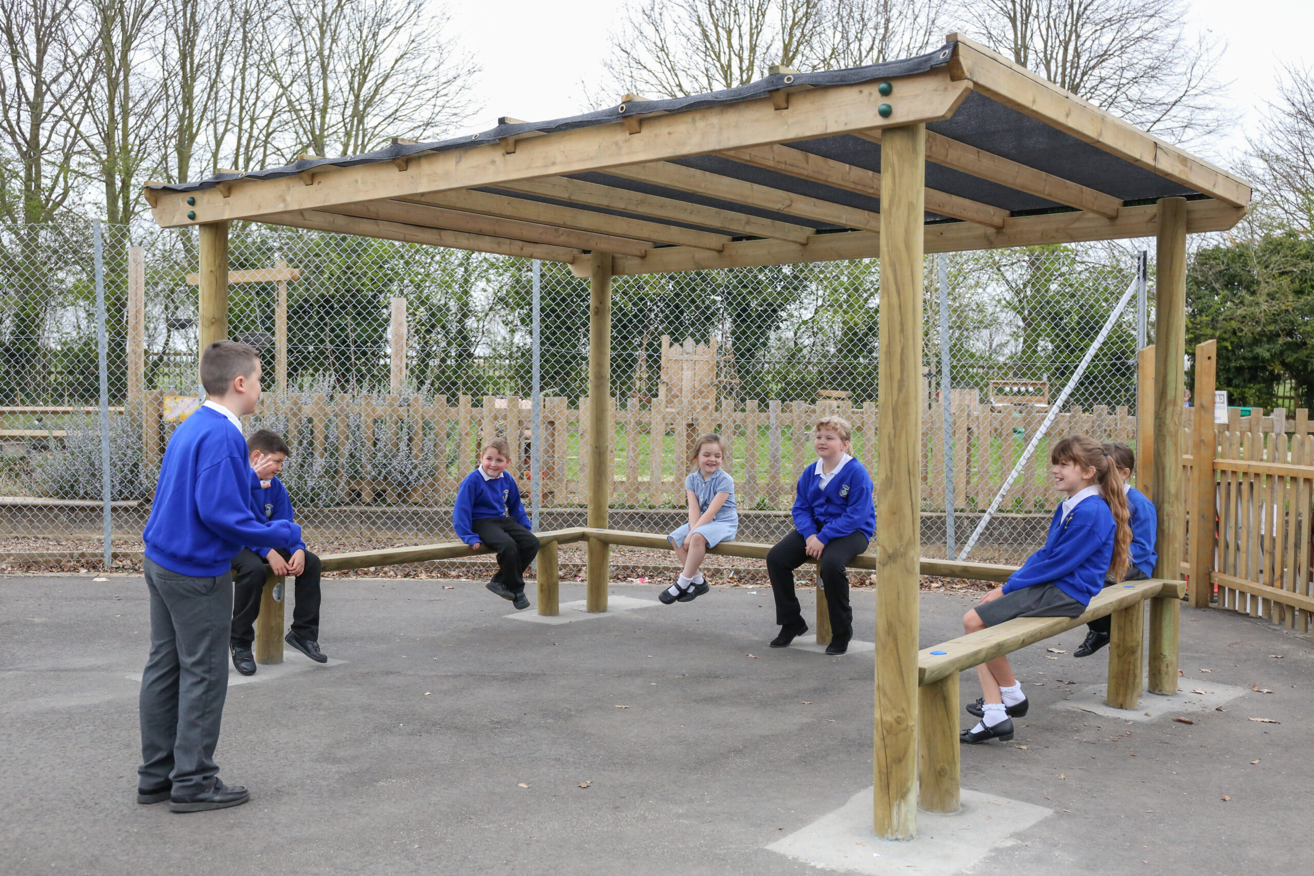 4 legged shade pergola with children sitting on the benches underneath