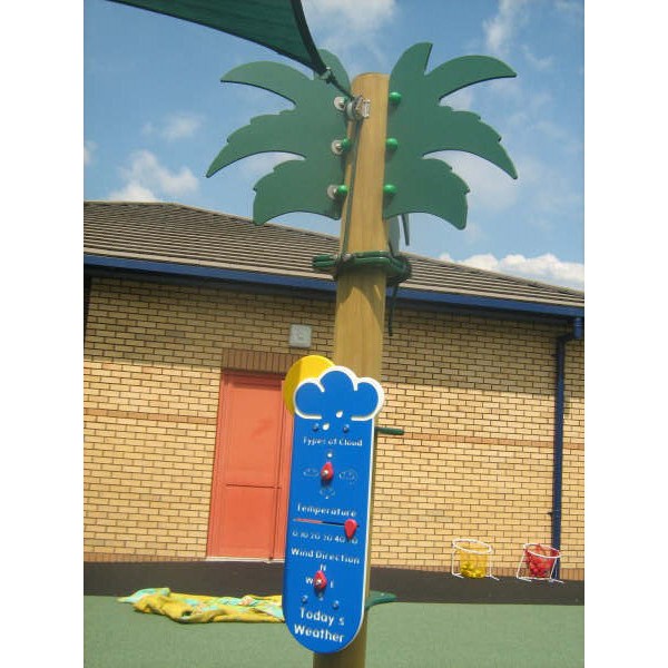 A playground weather station display shaped like a palm tree stands on rubber flooring with a brick building and toys in the background.
