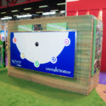 Large interactive wall panel with five coloured lights, installed on a wooden structure in an indoor exhibition space titled Learning ACTIV Zone.