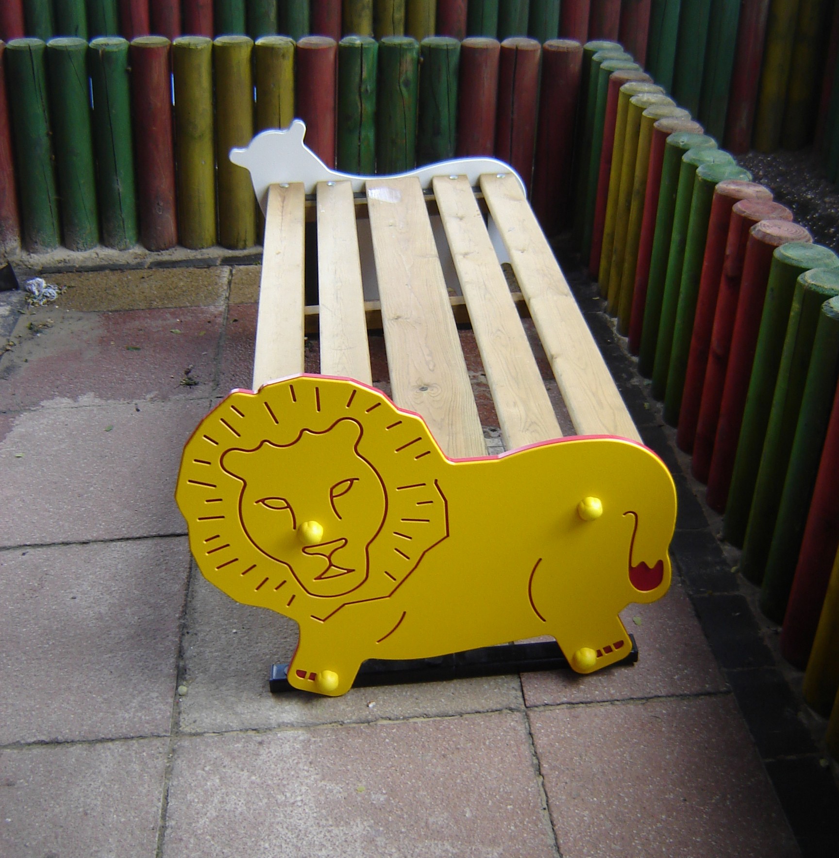 A wooden bench with a lion shape on one end and a white animal shape on the other, surrounded by colourful vertical wooden posts.