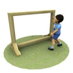 A young child in blue clothes stands on grass, touching a large wooden rectangular frame.
