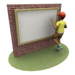 A person wearing a red cap and yellow shirt stands on grass, facing and touching a large blank framed board mounted on a brick wall.