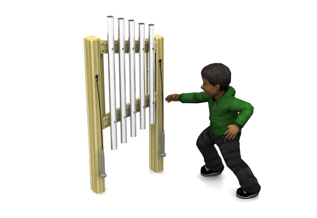 A child in a green hoodie stands next to an outdoor musical chime instrument, reaching towards the metal tubes with a mallet in hand.