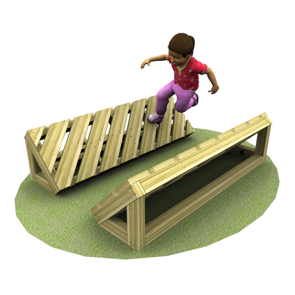 A young child in pink pants and a red shirt jumps over a wooden playground obstacle on a patch of grass.