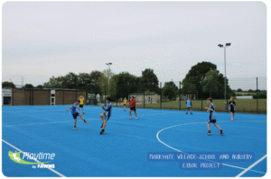 Markygate Primary School with a blue Multi Use Games areea with whote lines from Playtime by Fawns. Children playing football on the pitch