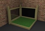 A wooden-framed enclosure with a glass side, a solid black panel, and a green artificial grass floor, placed in the corner of a brick-walled room.