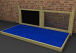 A wooden frame with two vertical posts and two panels stands on a blue carpeted platform in front of a brick wall. One panel is black, the other is clear.